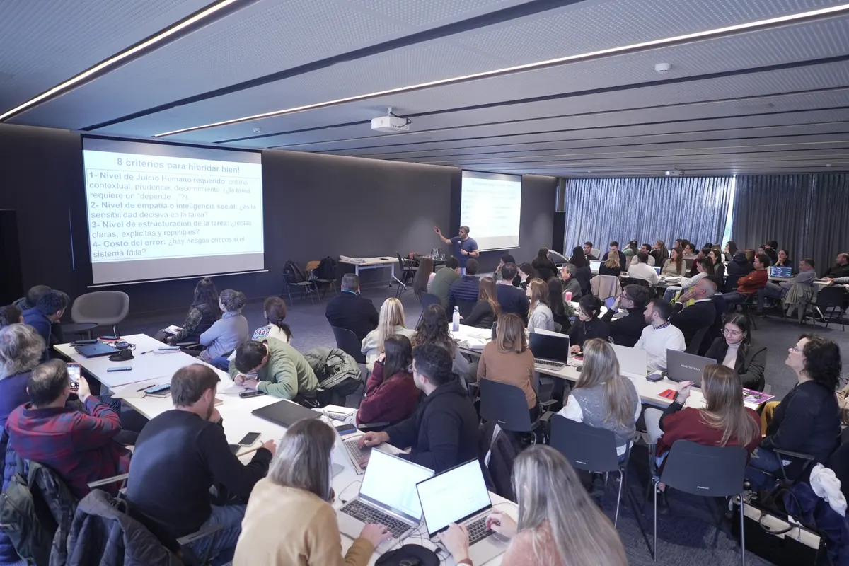 Sala llena durante un taller de rediseño de flujos, con los participantes trabajando en sus computadoras